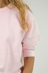Person wearing a light pink sweatshirt on a plain background