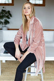 Young woman wearing blush velvet coat and black pants